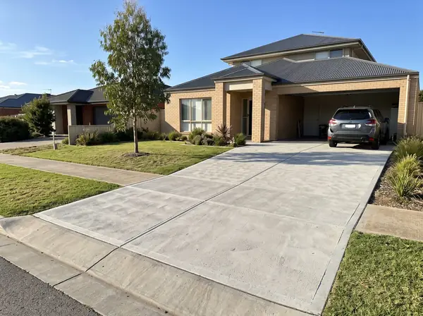 New broom-finished concrete double driveway and crossover at a brick veneer home in Adelaide