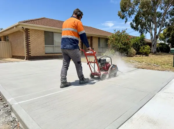 A concreter saw-cutting a control joint across a new driveway