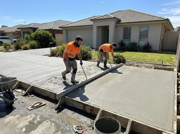 Two concreters screeding a freshly poured driveway