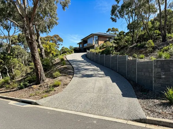 Steep exposed aggregate driveway climbing to a hillside home