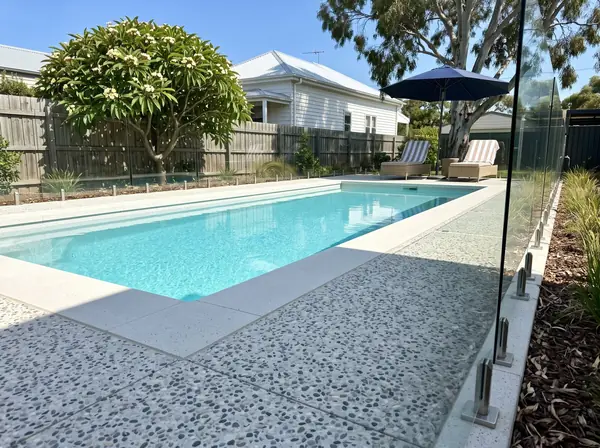 Coastal white exposed aggregate around a backyard pool