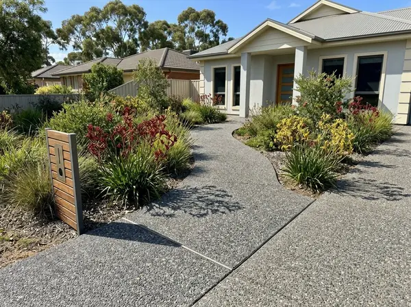 Curved charcoal exposed aggregate front path through a native garden