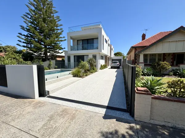 A new coastal white exposed aggregate driveway at a modern two-storey home on a narrow block a street back from the beach in Glenelg