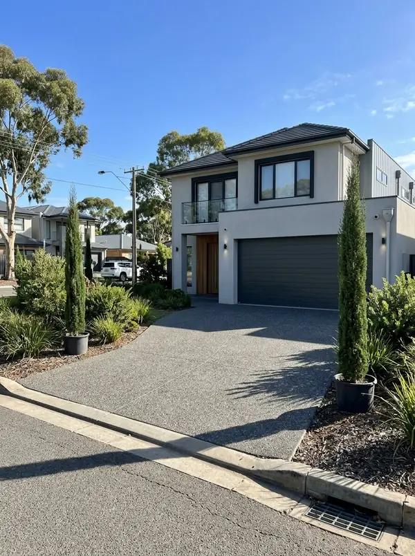 Charcoal exposed aggregate driveway at a two-storey home with pencil pines, Glenelg