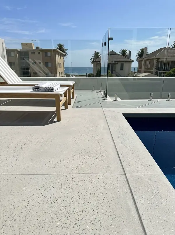 Light grey honed concrete pool deck with a striped sun lounge, Glenelg