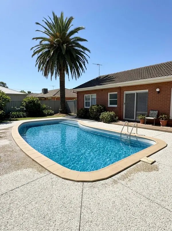 Pale exposed aggregate pool surround at a 1970s brick home, Glenelg North