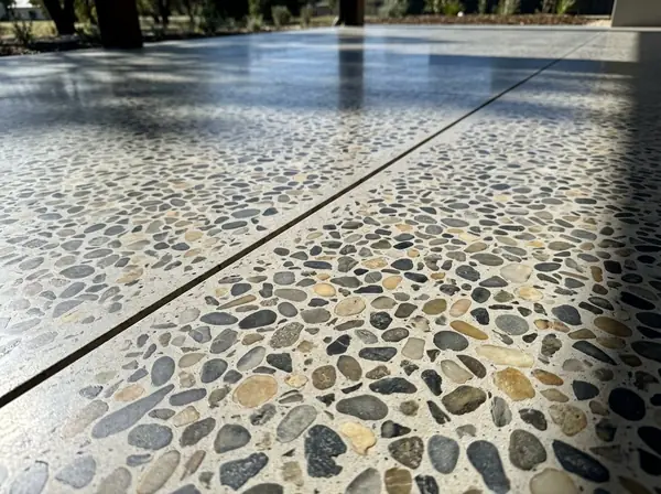 A close-up of a sealed full-exposure honed concrete surface with cut river stone