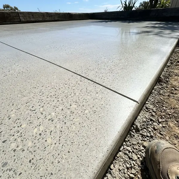 Close up of a sealed honed concrete surface with fine stone fleck and a saw-cut joint