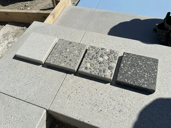 Four sealed honed concrete sample tiles of increasing stone exposure on a step