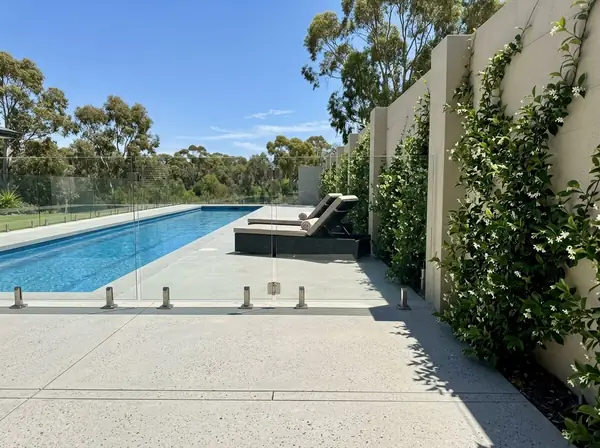 Pale honed concrete pool deck around a lap pool
