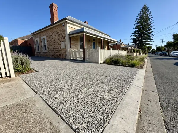 A new exposed aggregate driveway at a renovated stone workers' cottage on a flat street in Port Adelaide