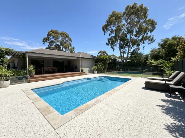 Pale exposed aggregate pool surround around a backyard pool in Adelaide