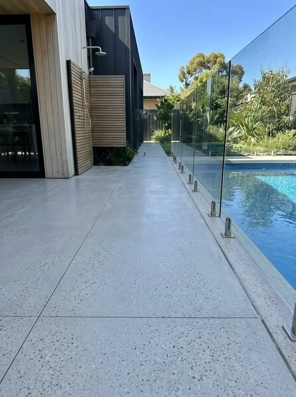 Light grey honed concrete pool deck with a glass fence and outdoor shower, Unley