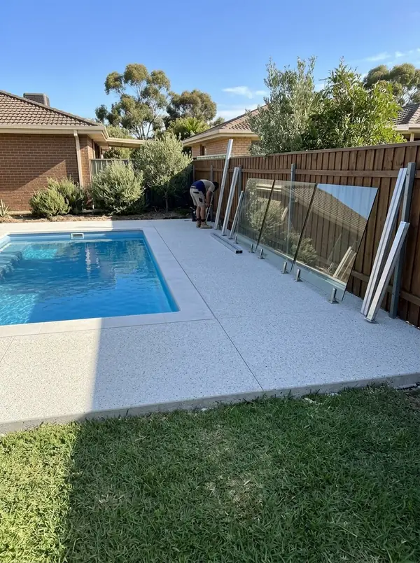 Pale exposed aggregate surround around a fibreglass pool being fenced, Aberfoyle Park