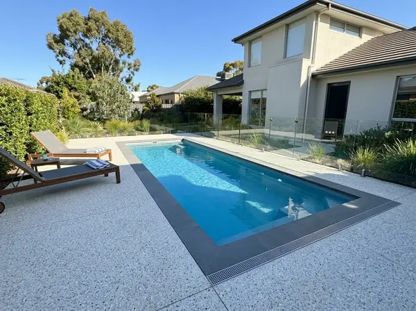 Pale exposed aggregate surround around a rectangular backyard pool