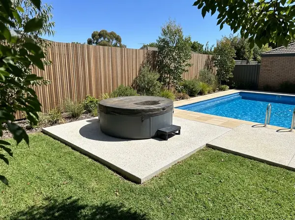 A concrete pad with a round spa on it beside a pool surround