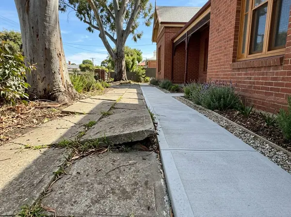 An old lifted concrete path with a trip step beside a new smooth section that replaces it
