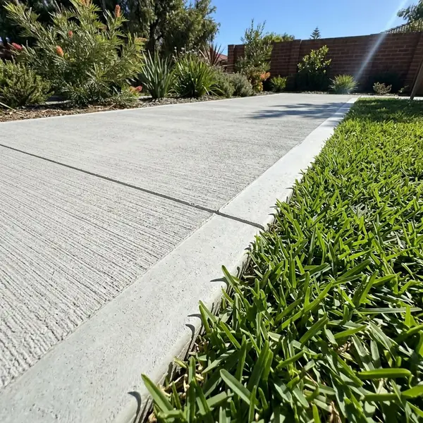 Close up of a new concrete path edge with a tooled edge meeting the lawn