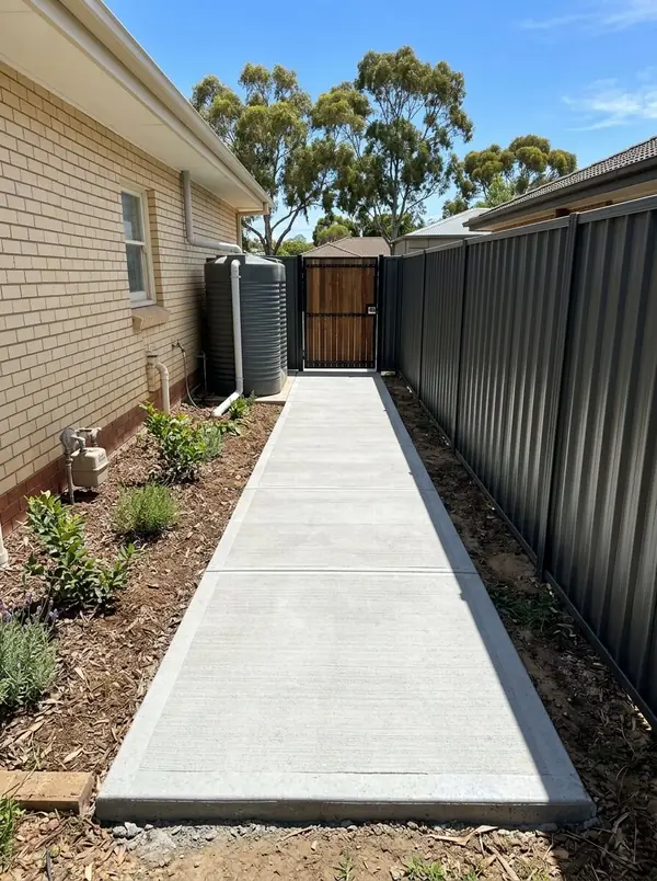 New broom-finished concrete side path between a cream brick home and a fence, Modbury