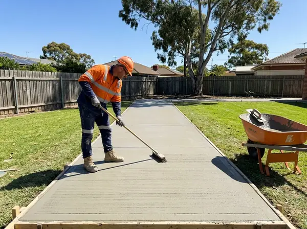 A concreter dragging a broom across a freshly floated path
