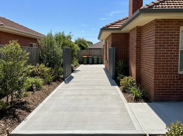 New concrete side access path along a brick home to a backyard