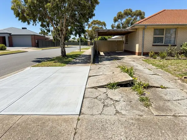 An old cracked Housing Trust driveway beside a neighbour's brand new broom-finished one on a flat Salisbury street