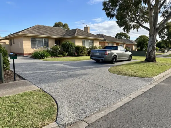A new exposed aggregate driveway and crossover at a 1960s cream brick home on a flat street in Salisbury