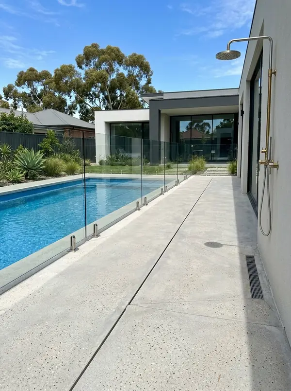 Light grey honed concrete pool deck with a glass fence, Unley